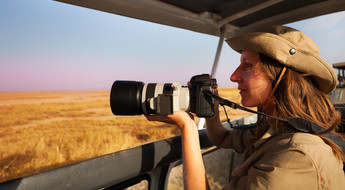 Femme à bord d'un 4x4 photographiant la savane