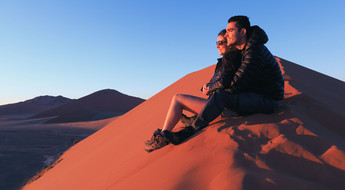 Couple admirant le lever du soleil sur les dunes de Namibie