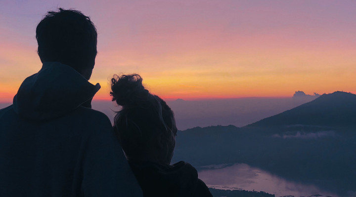 Couple admirant le lever du soleil face au mont Batur en Indonésie