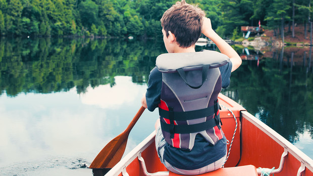 Enfant pagayant sur un lac au canada.