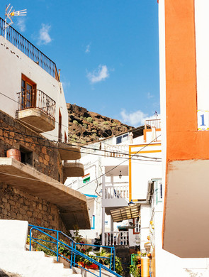 Une ruelle colorée d'une ville canarienne surplombée par la roche volcanique d'une falaise